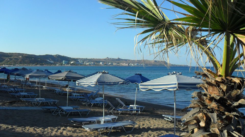 Sandstrand mit Sonnenschirmen und Blick über die Bucht von Faliraki