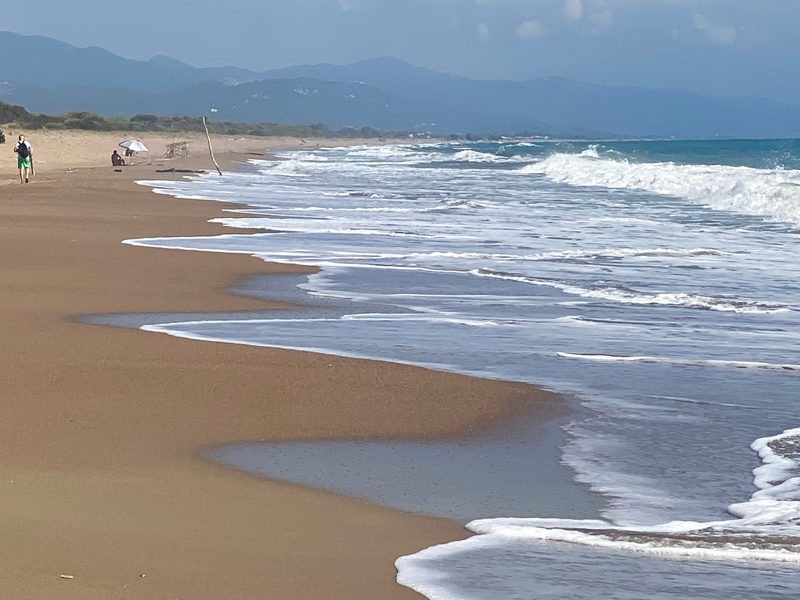 Auslaufende Brandung auf dem weiten Sandstrand von Kalogria auf dem Peloponnes, am Horizont die Berge des Festlands — zeigt nicht den genannten Ort
