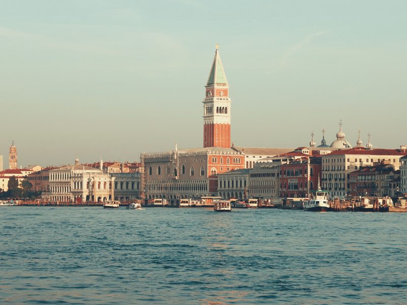 Der Campanile von San Marco überragt die Uferpaläste Venedigs, davor kreuzen Vaporetti auf dem Wasser — zeigt nicht den genannten Ort